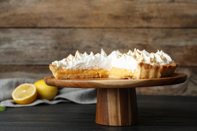 Photo of Stand with delicious lemon meringue pie on wooden table