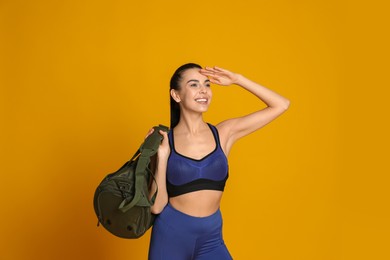 Photo of Beautiful woman with sports bag on yellow  background