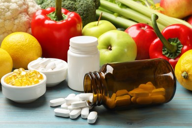 Photo of Dietary supplements. Bottles and bowls with different pills near food products on light blue wooden table