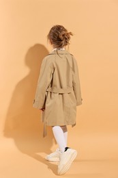 Photo of Fashion concept. Stylish girl posing on pale orange background, back view
