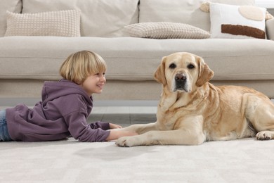 Photo of Cute little child with Golden Retriever on floor at home. Adorable pet