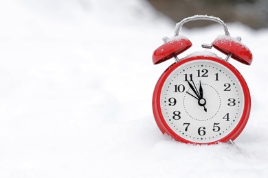 Red alarm clock on white snow outdoors. Space for text