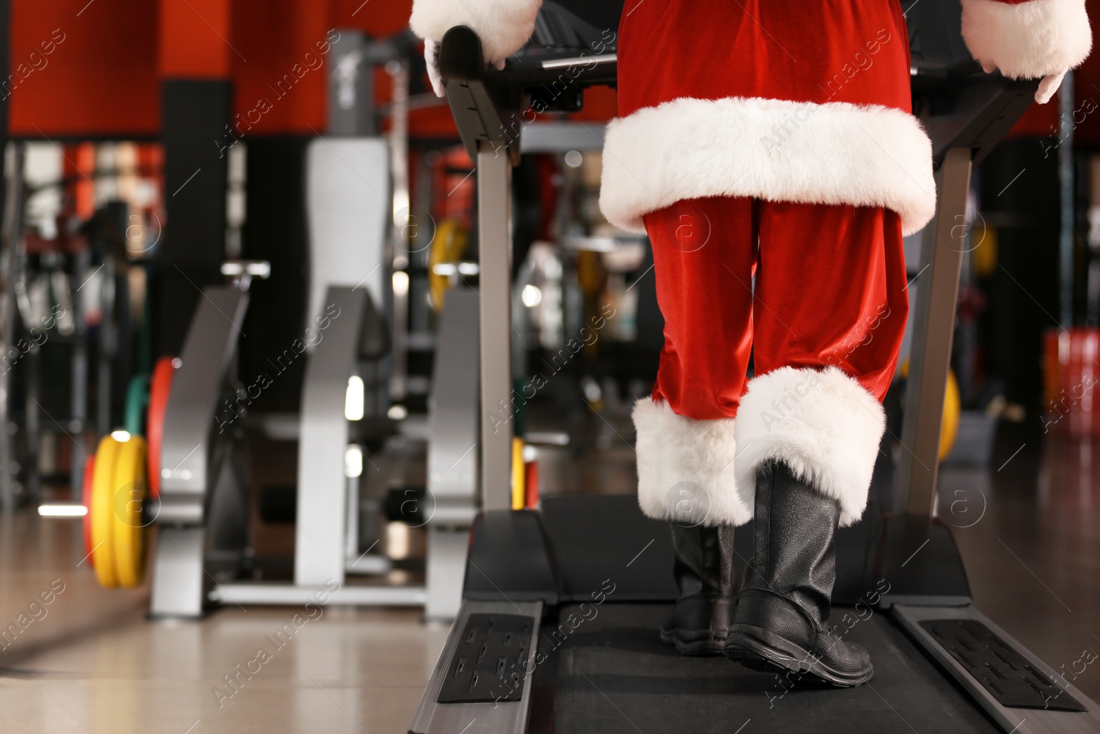Photo of Authentic Santa Claus training on treadmill in modern gym, focus on legs