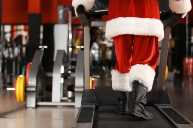 Photo of Authentic Santa Claus training on treadmill in modern gym, focus on legs