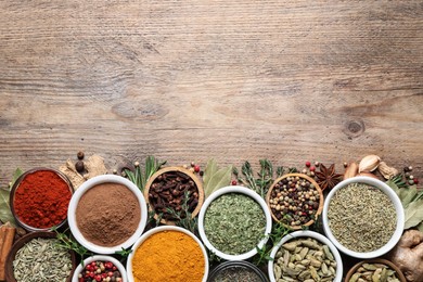 Flat lay composition with different natural spices and herbs on wooden table, space for text