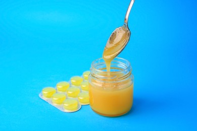 Photo of Blister with cough drops and honey on light blue background