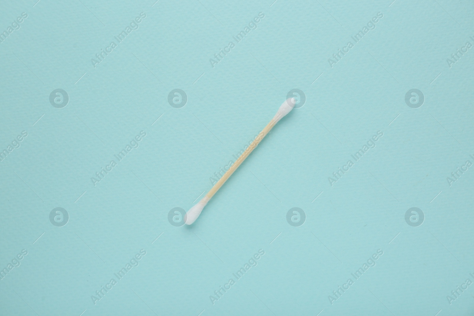 Photo of One wooden cotton bud on turquoise background, top view