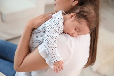 Photo of Woman holding her sleeping baby at home, closeup