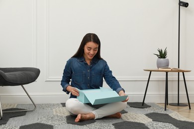 Happy young woman opening parcel at home. Internet shopping