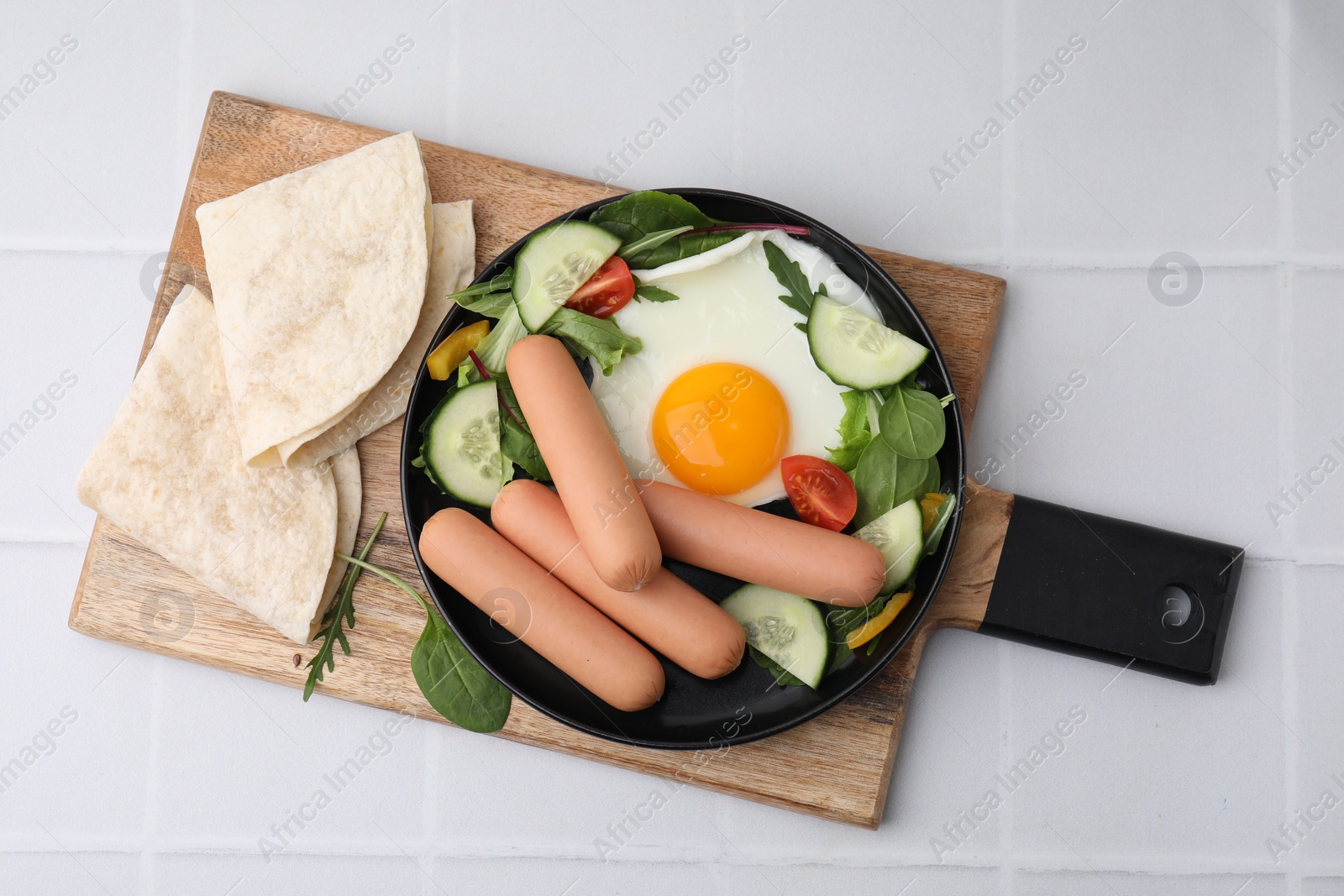 Photo of Delicious breakfast with boiled sausages and fried egg on white tiled table, top view