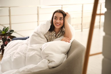 Photo of Beautiful young woman wrapped with soft blanket relaxing on sofa at home