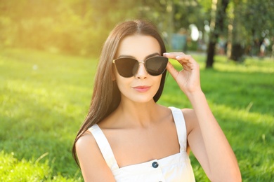 Photo of Beautiful young woman wearing stylish sunglasses in park