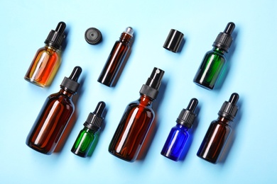 Flat lay composition with cosmetic bottles of essential oils on color background