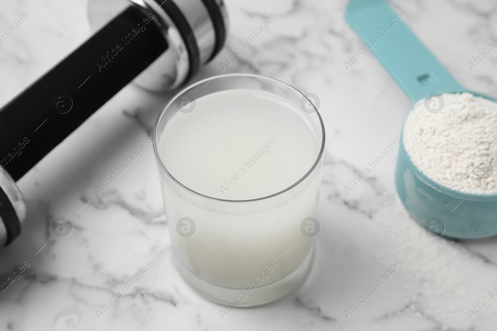 Photo of Amino acid shake, powder and dumbbell on white marble table