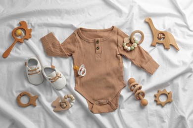 Photo of Flat lay composition with cute baby clothes and accessories on white bedsheet