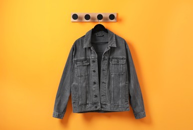 Photo of Hanger with dark gray denim jacket on orange wall