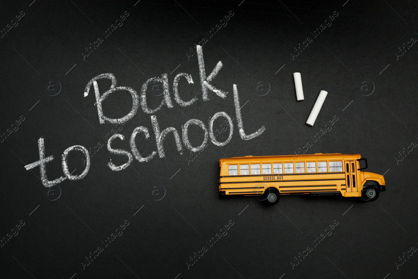 Photo of Yellow bus and phrase "Back to school" on chalkboard, top view. Transport for students