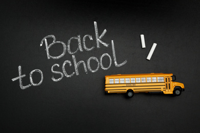 Photo of Yellow bus and phrase "Back to school" on chalkboard, top view. Transport for students