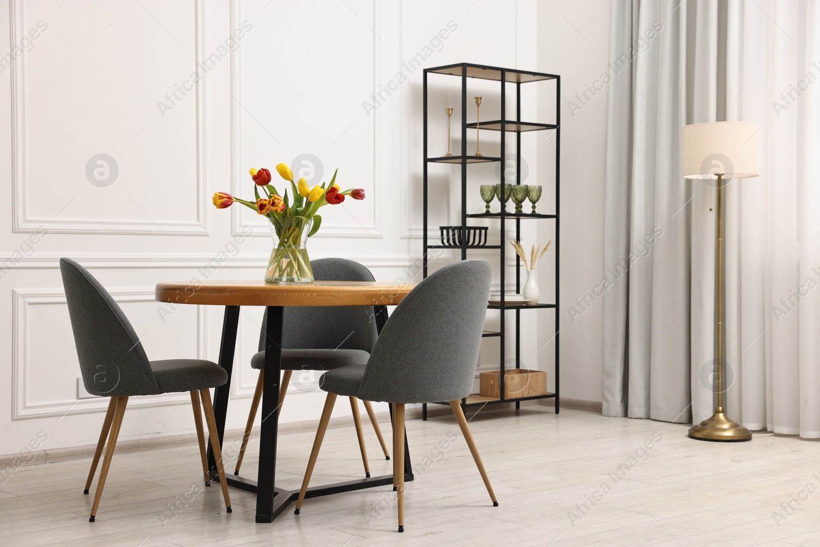 Photo of Stylish dining room interior with comfortable furniture and beautiful tulips