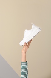 Photo of Woman holding sportive shoe on color background, closeup. Space for text