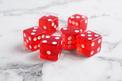 Many red game dices on white marble table, closeup