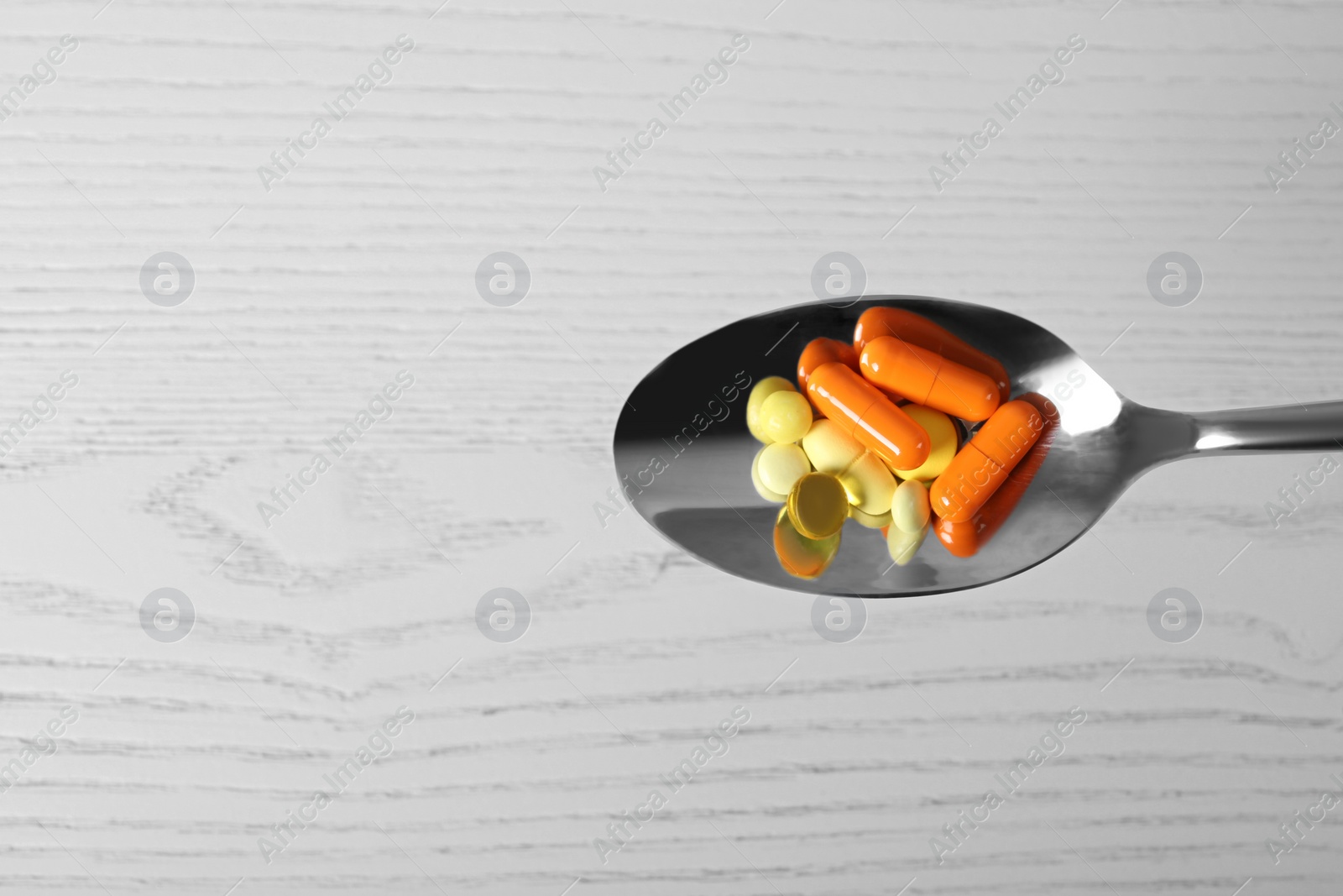 Photo of Spoon with weight loss pills on light background, top view