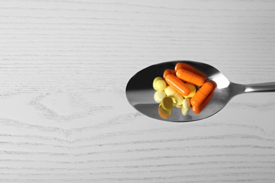 Photo of Spoon with weight loss pills on light background, top view