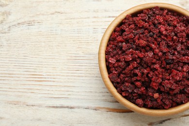 Wooden bowl with dried red currant berries on white table, top view. Space for text