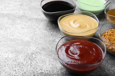 Photo of Many different sauces on grey table, space for text