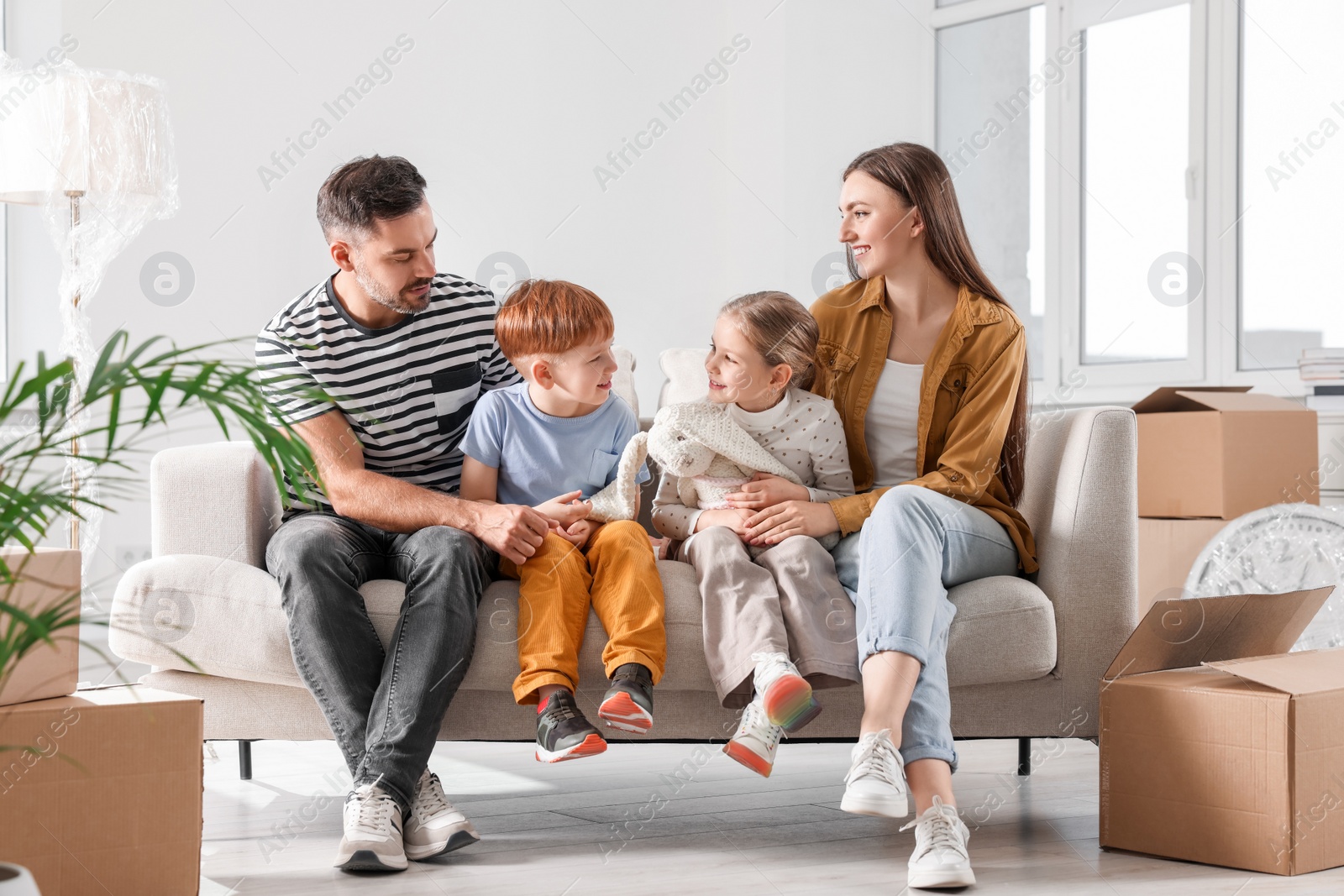 Photo of Happy family sitting on couch in new apartment. Moving day