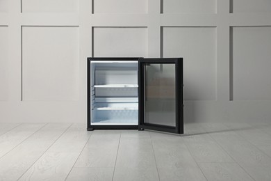 Photo of Empty mini bar with open glass door near beige wall indoors