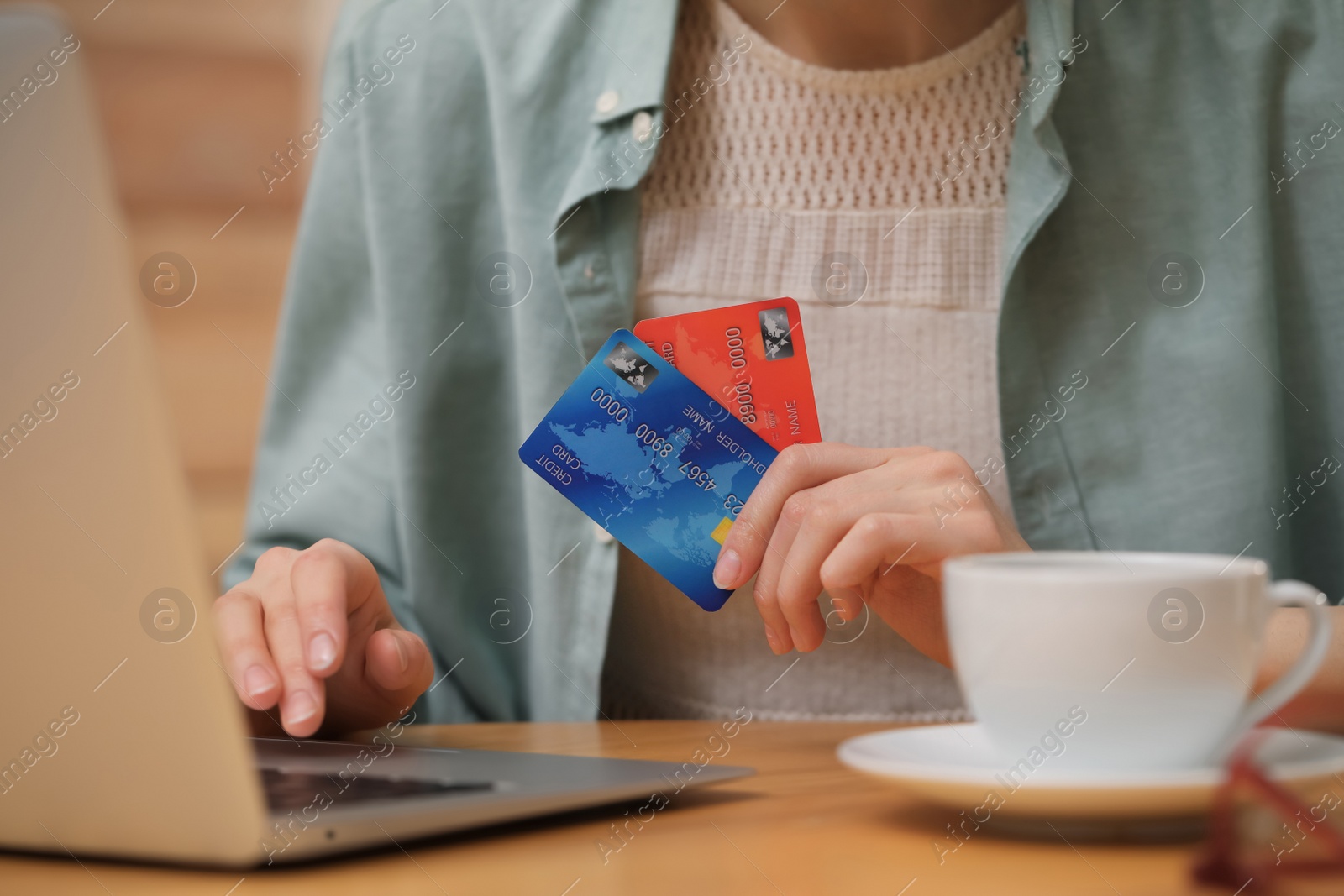 Photo of Woman with credit cards using laptop for online shopping at wooden table, closeup