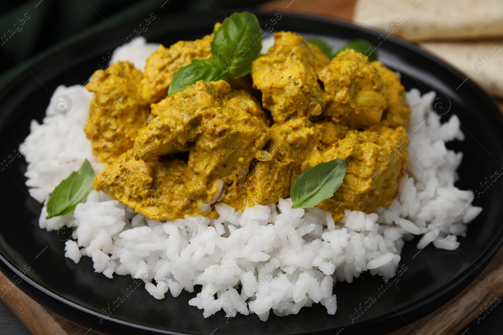 Photo of Delicious rice and chicken with curry sauce on plate, closeup