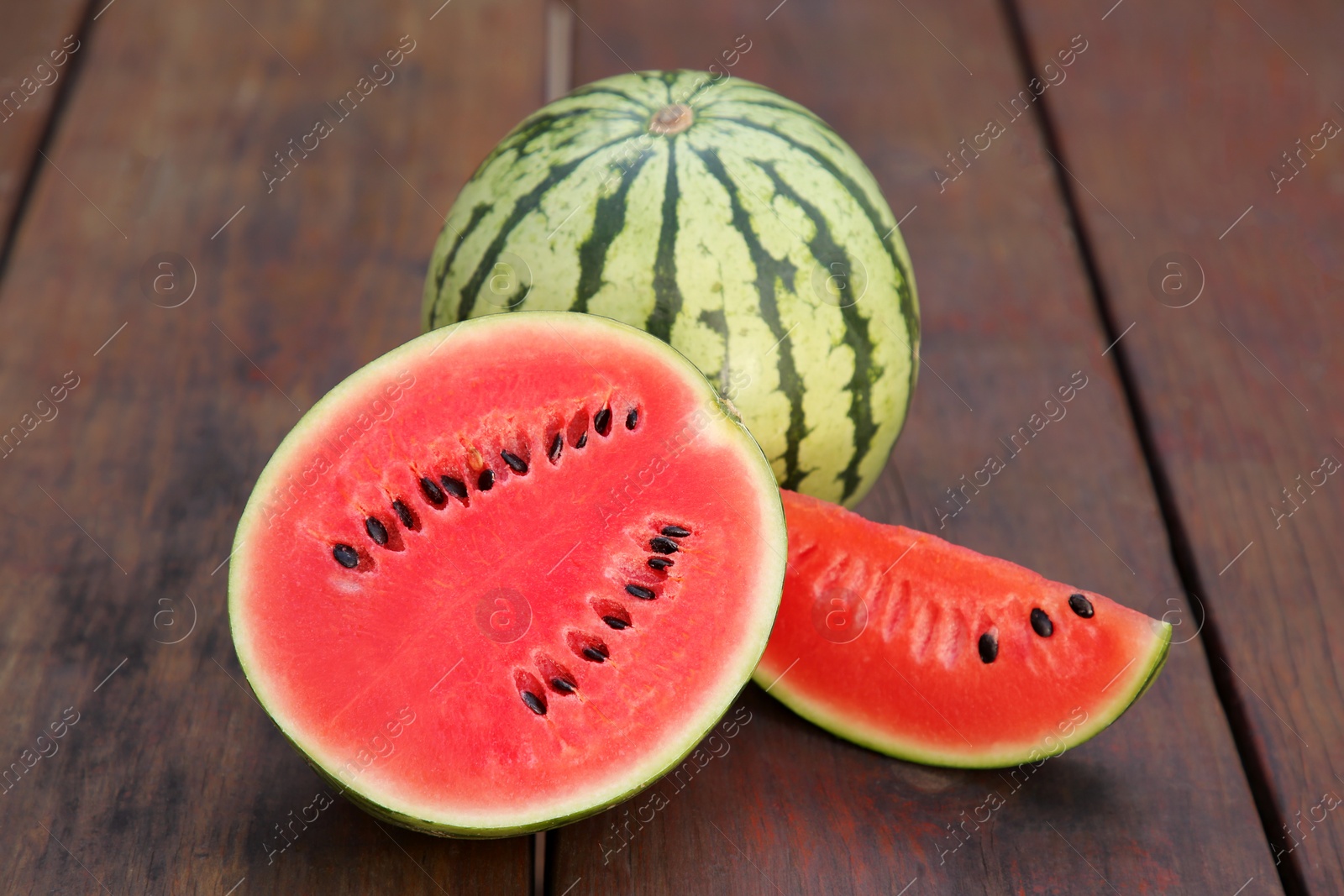Photo of Delicious cut and whole ripe watermelons on wooden table