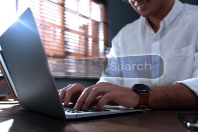 Image of Search bar of website over laptop. Man using computer at wooden table, closeup