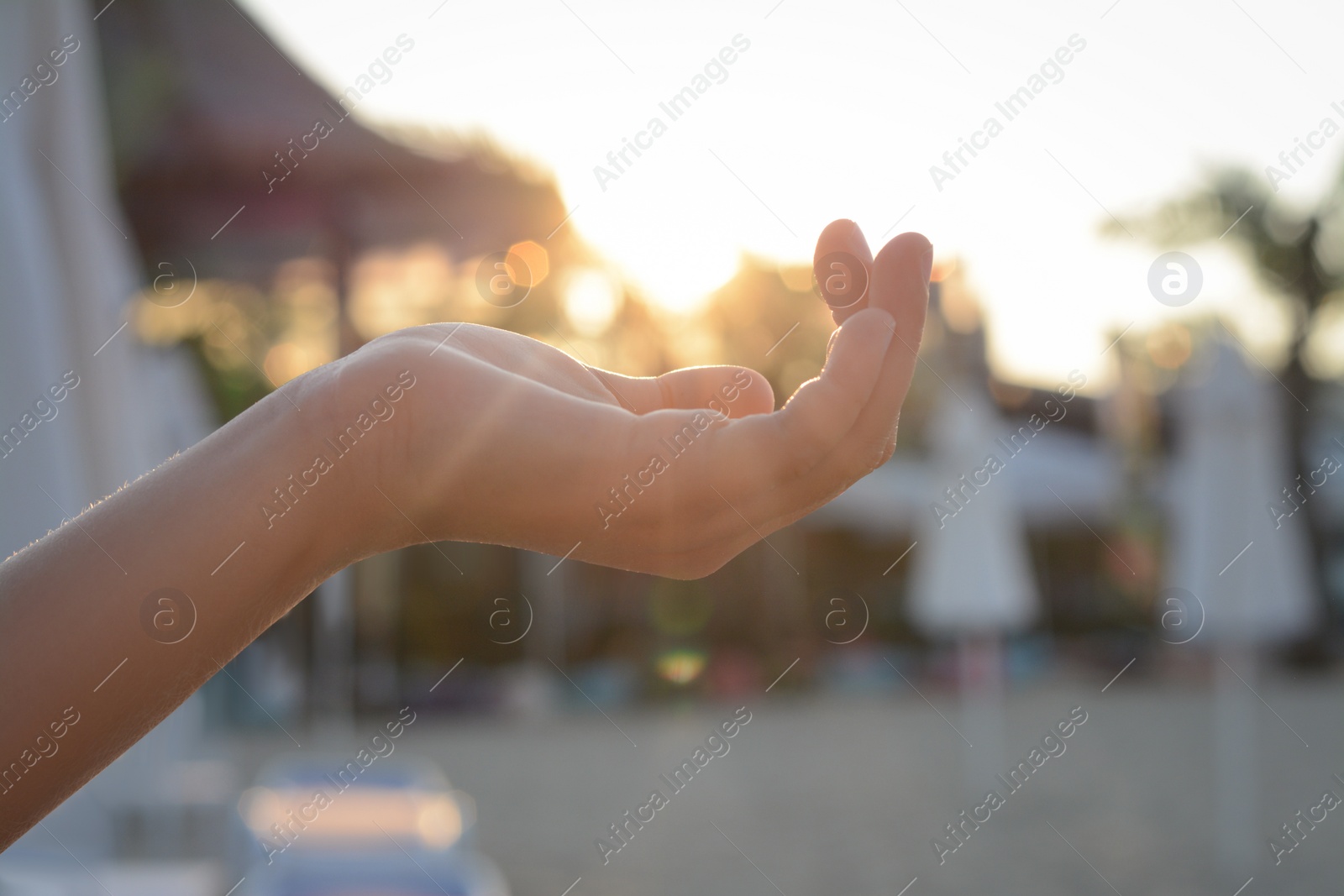 Photo of Girl holding her hand against sunlight on beach, closeup