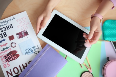Photo of Female beauty blogger with tablet and makeup brush at table, top view