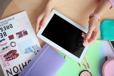 Female beauty blogger with tablet and makeup brush at table, top view