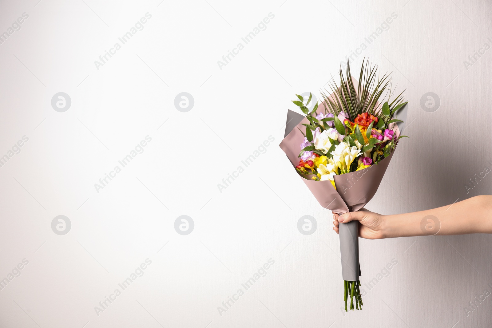 Photo of Woman with beautiful bouquet of freesia flowers on white background