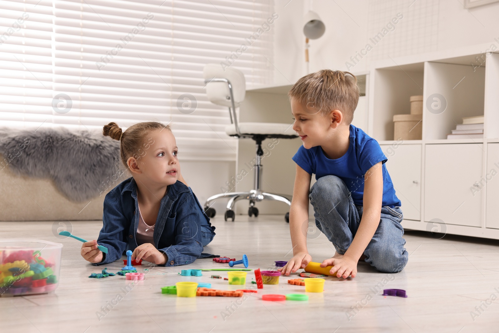 Photo of Cute little children playing on warm floor at home. Heating system