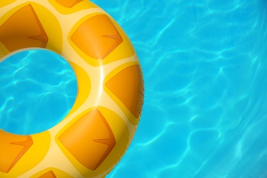 Bright inflatable ring floating in swimming pool on sunny day. Space for text