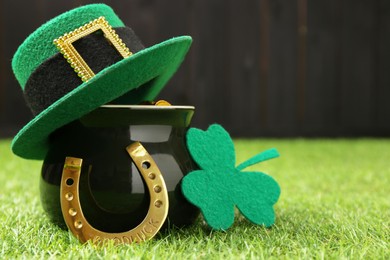 St. Patrick's day. Pot of gold with leprechaun hat, horseshoe and decorative clover leaf on green grass. Space for text