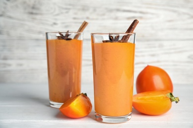 Tasty persimmon smoothie with anise and cinnamon on white wooden table