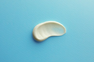 Photo of Sample facial cream on turquoise background, top view