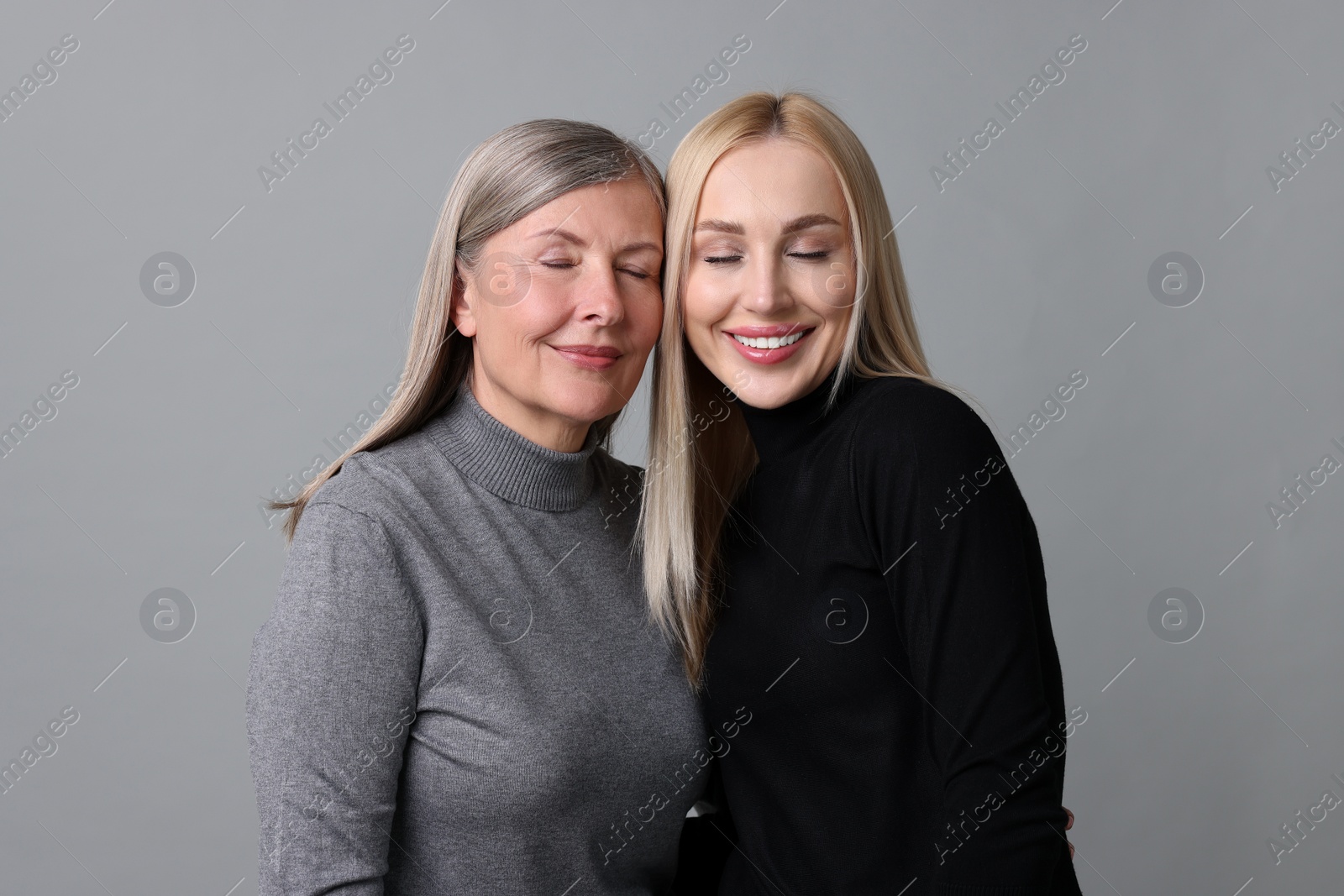 Photo of Family portrait of young woman and her mother on grey background