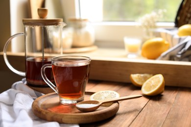 Photo of Delicious tea, sugar and lemon on wooden table, space for text