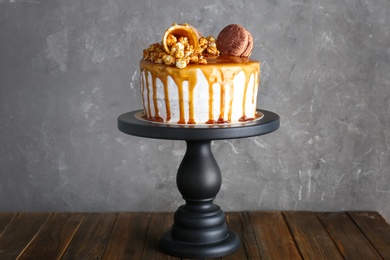 Photo of Dessert stand with delicious caramel cake on table against gray background