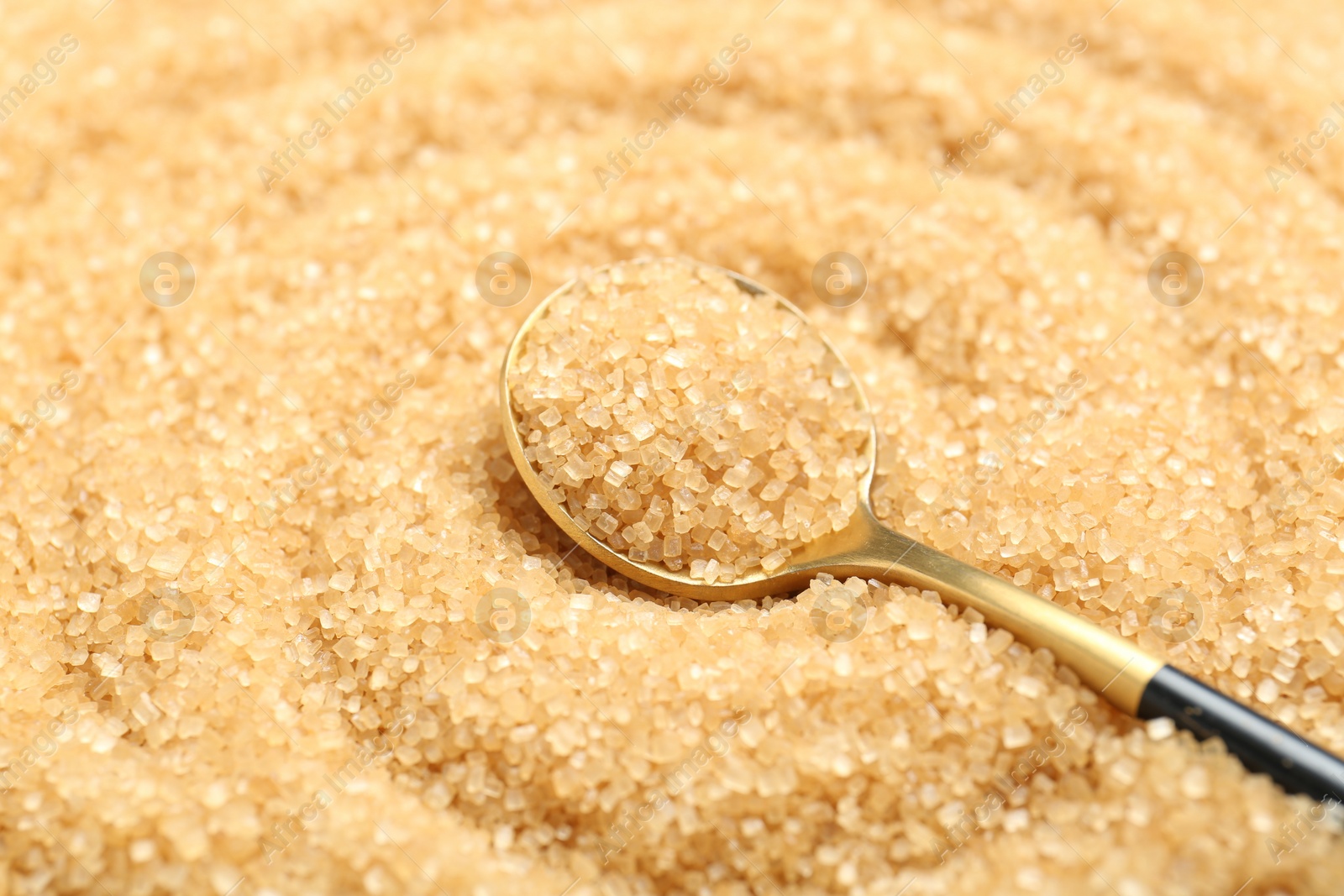 Photo of Spoon on granulated brown sugar, closeup view