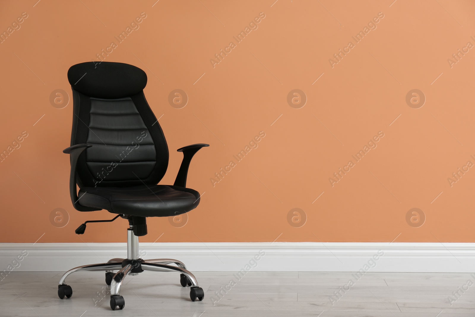 Photo of Modern office chair near orange coral wall indoors. Space for text