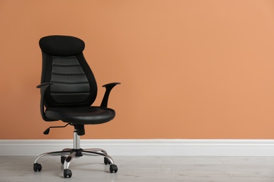 Modern office chair near orange coral wall indoors. Space for text